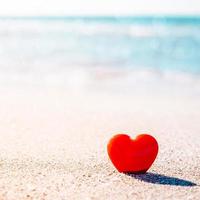 símbolo romántico de corazón rojo en la playa de arena foto