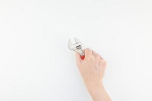 Female hand holding spanner on white background photo