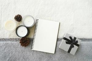 Top view of cozy warm mood with blank notebook planner on knitted background and candle with gift box, thanksgiving and holiday concept photo