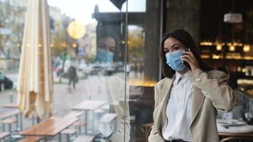 vrouw tolken Aan de telefoon op zoek door koffie winkel venster video