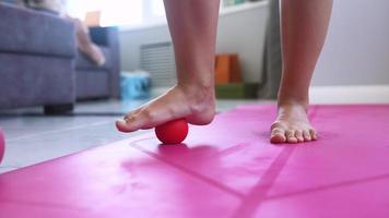 Woman exercising with rubber ball on pink mat in living room video