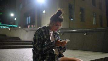Girl using her phone at city at night video