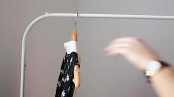 Frau schaut auf Kleider, die an einem Gestell hängen video