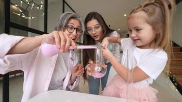 poco ragazza giocando con chimica tubi a casa con famiglia video