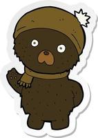 sticker of a cartoon cute black bear in winter hat and scarf vector