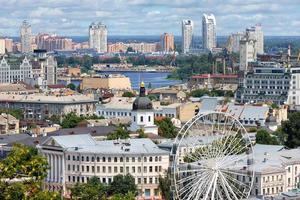 Ferris wheel in the old Podil district against the backdrop of new houses in the Obolon sleeping area on the horizon. 07.24.22. Kyiv. Ukraine. photo