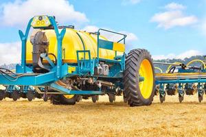 A fragment of a modern agricultural seeder against a yellow field and a blue sky. photo