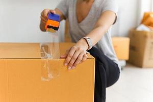 Asian business woman packing product sealing cardboard with duct tape. photo