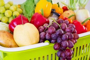 Fresh fruits and vegetables in green shopping basket photo