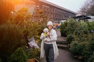 Woman with a white dog in her arms near a green Christmas trees photo