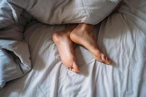 Close-up woman feet alone in white bed photo