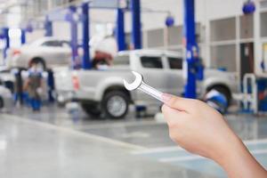 Technician holding a wrench with car repair service center background photo