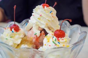 ice cream in glass bowl with whipped cream and red cherry on top photo