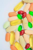 Many colorful pills on white background photo