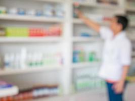 blur pharmacist taking medicine from shelf in the pharmacy photo