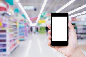 mujer que usa un teléfono inteligente móvil mientras compra en una tienda de supermercado foto