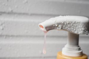 gota de agua en la bomba dispensadora de jabón líquido durante el baño foto