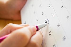 página de calendario con pluma de mano femenina foto