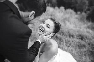 groom gently touches the face of his bride photo