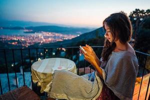 Woman sits on the balcony, in the background the night city photo