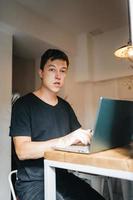 Portrait of man sitting at a table at home working on a laptop. photo