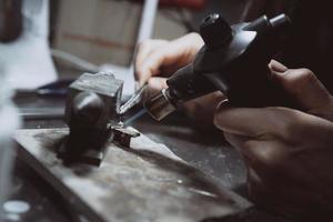 In the workshop, a woman jeweler is busy soldering jewelry photo