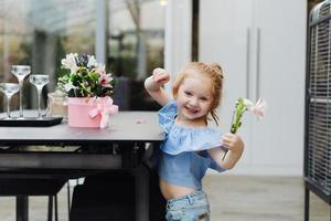 Little girl puts flowers on table photo