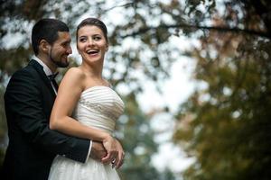 groom embracing bride from back photo