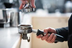 Barista presses ground coffee using tamper. photo