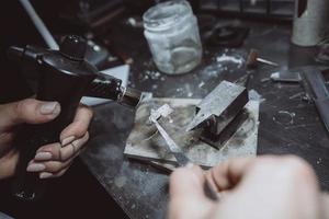 In the workshop, a woman jeweler is busy soldering jewelry photo