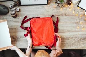 Woman wrapping present in paper with red ribbon. photo