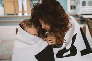 Cute little girl and her beautiful young mom hug each other photo