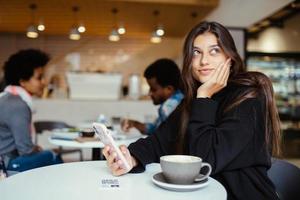 Female student using smartphone while sitting in cafe photo