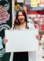 Smiling brunette woman holding white blank board photo
