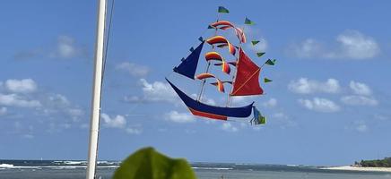 flying ship, rainbow colored ship kite flies on the blue sky and cloud photo