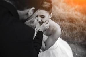 groom gently touches the face of his bride photo