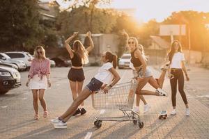 las mujeres jóvenes con un carrito de supermercado se divierten foto