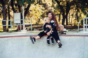 Beautiful young hipster mom and little son at the skatepark photo