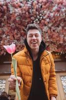 un hombre guapo tiene una flor, un tulipán rosa para su novia foto