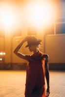 The young, attractive girl in a hat poses to the camera at night photo