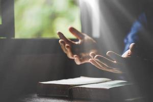 Hand folded in prayer to god on Holy Bible book in church concept for faith, spirituality and religion, woman person praying on holy bible in morning. christian catholic woman hand with Bible worship. photo