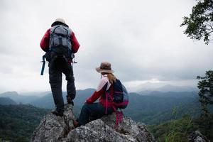 Young tourist couple watching spectacular mountain scenery in high mountains. man and woman hiker on top rock. A couple of travelers in love. People greet the dawn. Lovers travel. Copy space photo