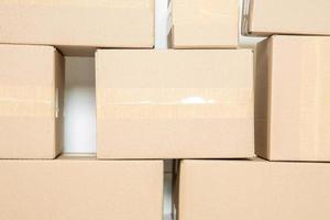 Stack of cardboard boxes for moving, Empty room with a white wall and cardboard boxes with unbranded barcode on the floor. Delivery of goods, shopping. Cardboard boxes on gray wall background. photo