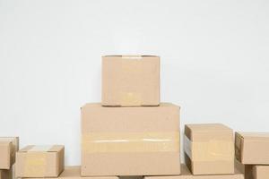 pila de cajas de cartón para mudanzas, habitación vacía con una pared blanca y cajas de cartón con código de barras sin marca en el suelo. entrega de mercancías, compras. cajas de cartón sobre fondo de pared gris. foto