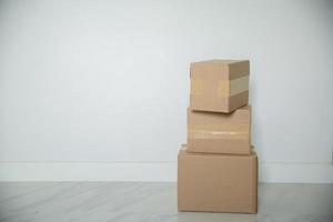 Stack of cardboard boxes for moving, Empty room with a white wall and cardboard boxes with unbranded barcode on the floor. Delivery of goods, shopping. Cardboard boxes on gray wall background. photo