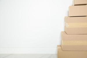 Stack of cardboard boxes for moving, Empty room with a white wall and cardboard boxes with unbranded barcode on the floor. Delivery of goods, shopping. Cardboard boxes on gray wall background. photo