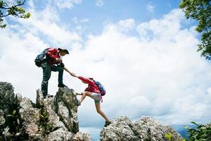 Person hike friends helping each other up a mountain. Man and woman giving a helping hand and active fit lifestyle. Asia couple hiking help each other. concept of friendship, teamwork. photo