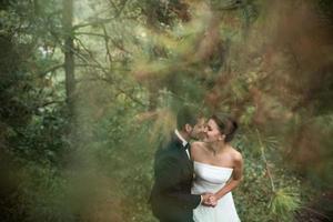 la novia y el novio bailan juntos en el bosque foto