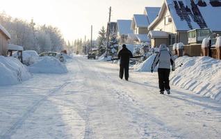 Frosty rural road landscape. Winter snow-covered rural road. People are coming from a ski trip, faces are not visible photo