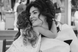 Cute little girl and her beautiful young mom hug each other photo